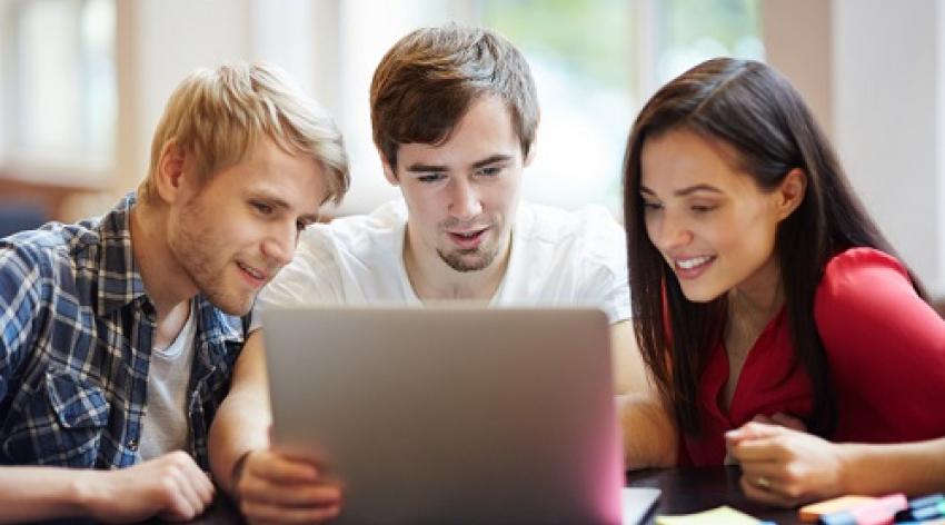 Three college students looking at a laptop 
