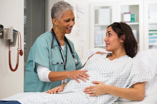 A doctor and a pregnant patient talking to each other.