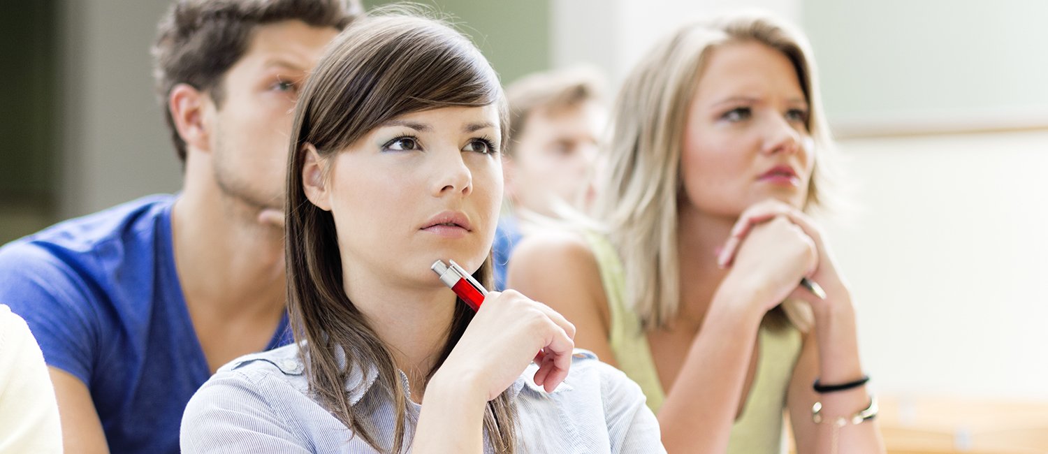 young woman sits in a lecture hall, looking forward