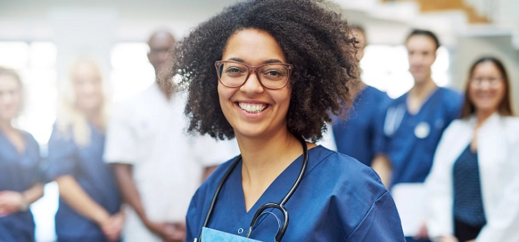 Female Doctor with glasses smiling wearing scrubs 