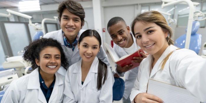 A group of medical students wearing white coats in a laboratory.