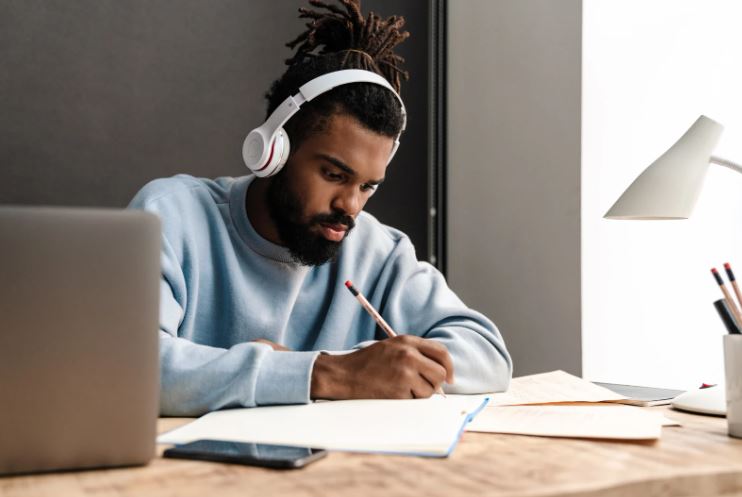 College student studying with headphones on and laptop in background