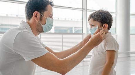 Adult adjusting a child's mask.
