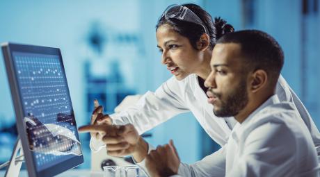 Two scientists look at a computer screen in a lab