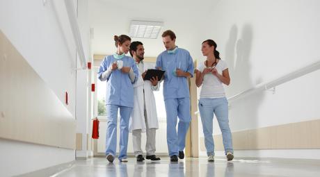 A group of four doctors talk in a hospital hallway