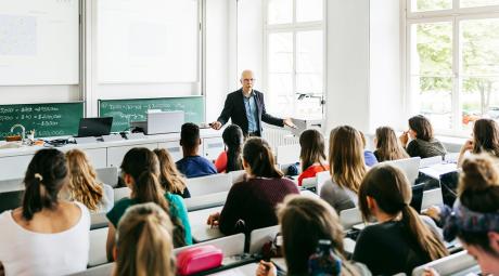 A teacher gives a lecture to a room full of students