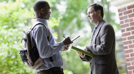 student talking with a professor near campus green