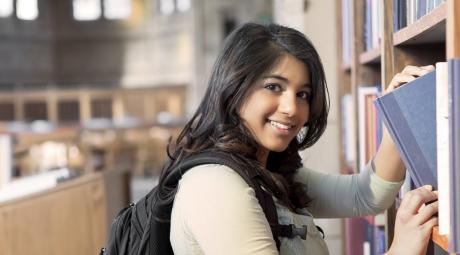 young student with backpack in library stacks