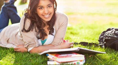 A shot of an asian student studying on campus lawn.