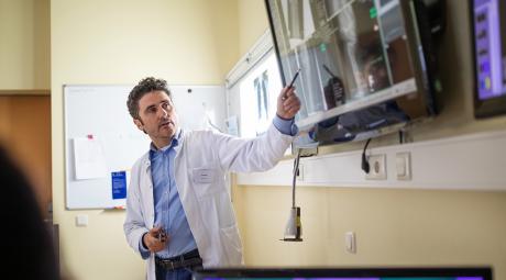 A physician teaches while pointing to a screen