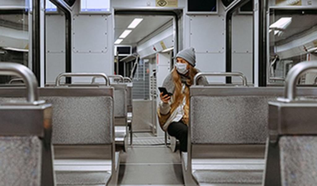 A person wearing a mask inside an empty train