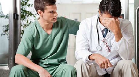 Nurse in green scrubs consoling a stressed doctor