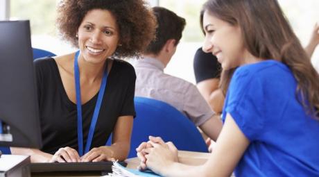 African-American lady and student smiling at computer screen.