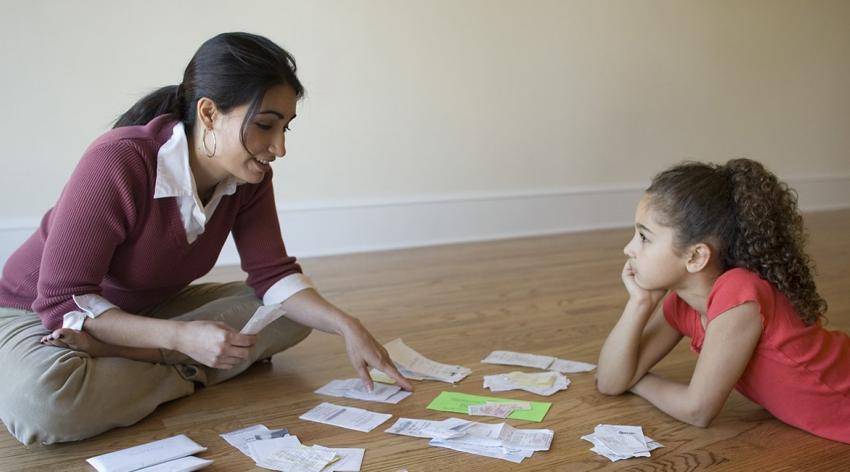 young mother sitting on floor with her daughter, paying bills