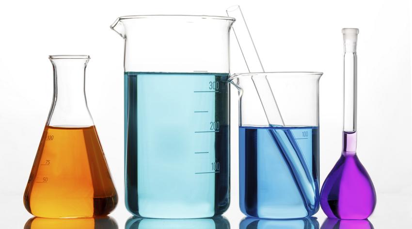 Four beakers with orange, blue, and purple liquid