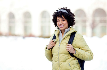 Student in jacket with backpack in a winter setting. 